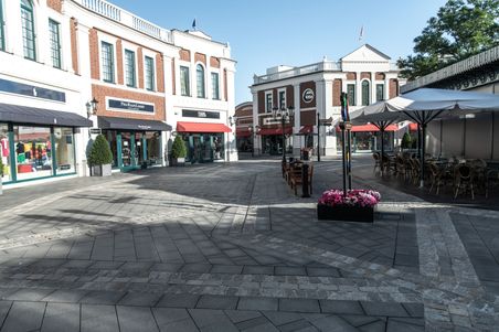 Einkaufsstraße im Outlet-Center Neumünster mit Geschäften und Cafés. Die Architektur ist modern mit roten Ziegeln und weißen Fassaden.
