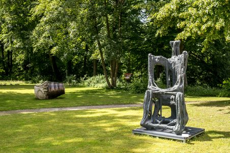 Skulpturen im Gerisch-Skulpturenpark Neumünster, umgeben von grünen Bäumen und Rasenflächen. Eine große, abstrakte Skulptur steht im Vordergrund.