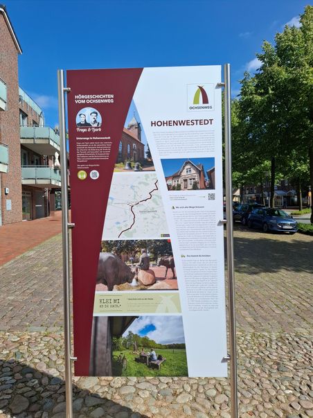 Ein Informationsschild in Hohenwestedt über den Ochsenweg. Es zeigt eine Karte, Fotos und Texte zur Geschichte und Sehenswürdigkeiten der Region.