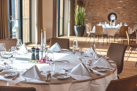 Festlich gedeckter Tisch im Hotel Breitenburg in einem hellen Speisesaal mit Kerzen, Gläsern und Blumen.