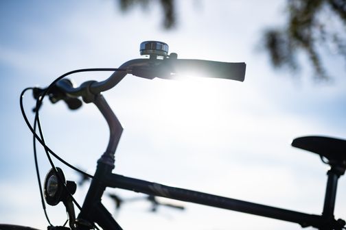 Ein Fahrradlenker im Gegenlicht der Sonne, das Licht strahlt durch die Griffe. Der Himmel ist klar und blau.