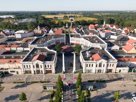 Luftaufnahme des Outlet-Centers Neumünster mit seinen charakteristischen Gebäuden und der umliegenden grünen Landschaft.