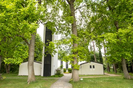 Die Kreuzkirche Schülp ist von üppigem Grün umgeben. Der weiße Bau mit schwarzem Turm fügt sich harmonisch in die Natur ein.