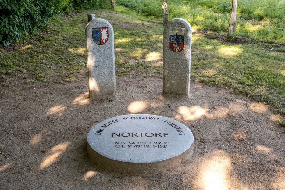 Geografischer Mittelpunkt in Schleswig-Holstein, runde Steinplatte mit der Aufschrift "Die Mitte Schleswig-Holsteins, Nortorf" und die Koordinaten