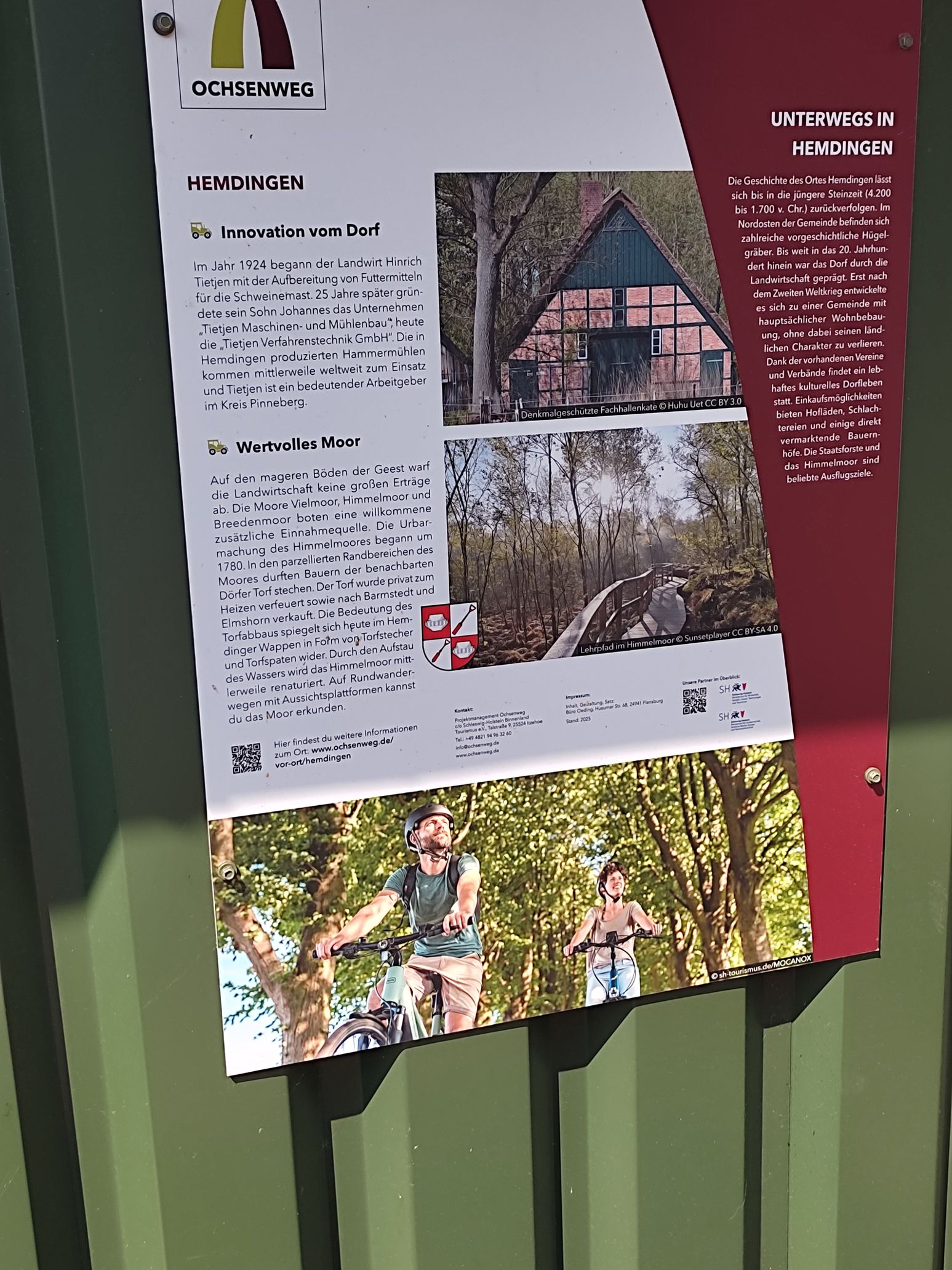 Informationsschild über den Ochsenweg in Hemdingen mit Details zur Geschichte und Natur der Region. Enthält Bilder von Fachwerkhaus und Radfahrern.