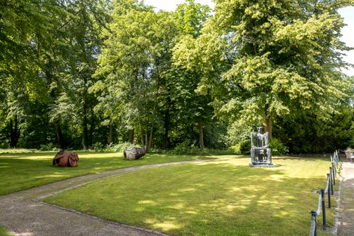 Skulpturen im Gerisch-Skulpturenpark Neumünster, umgeben von üppigem Grün und Bäumen. Ein gepflegter Weg führt durch die Anlage.