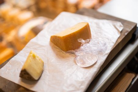 Zwei Käsestücke liegen auf einem Holzbrett. Der Hintergrund ist unscharf.