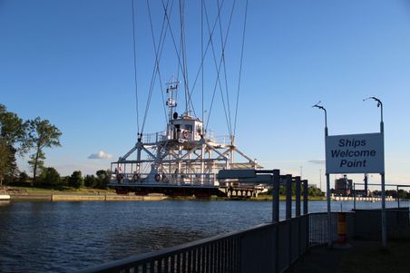 Die Schwebefähre Rendsburg überquert den Nord-Ostsee-Kanal. Ein Schild mit der Aufschrift 'Ships Welcome Point' ist sichtbar.