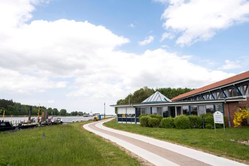 Die Lotsenstation Rüsterbergen liegt malerisch am Ufer eines Kanals. Ein Weg führt am modernen Gebäude vorbei, umgeben von grüner Natur.