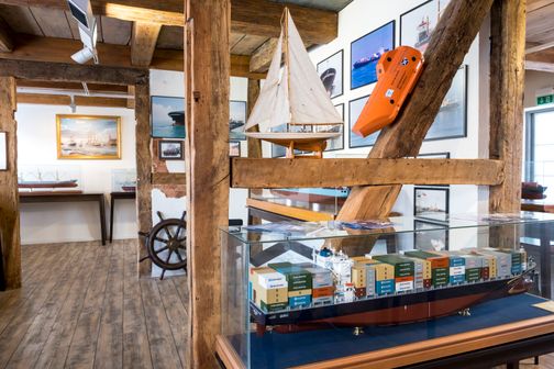 Das Schifffahrtsarchiv Rendsburg zeigt Modelle von Containerschiffen und Segelbooten sowie maritime Bilder an Holzwänden.
