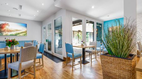 Liebevoll engerichteter Frühstückraum mit Tischen, Stühlen und Sitzbänken mit Sicht in den Innnenhof des Hotels