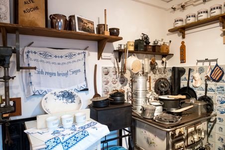 Historische Küchenausstellung im Dorfmuseum Fockbek mit alten Küchenutensilien, einem Herd und dekorativen Fliesen.