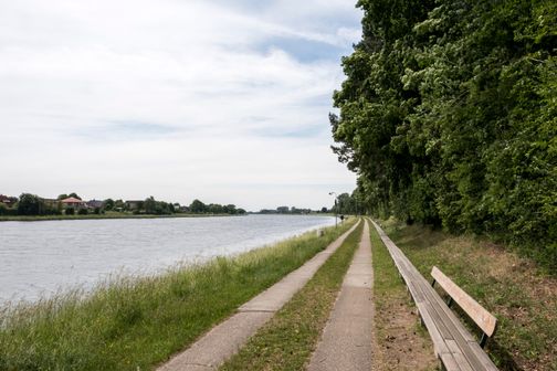 Die längste Bank der Welt verläuft entlang des Nord-Ostsee-Kanals, flankiert von einem Gehweg und üppigem Grün.