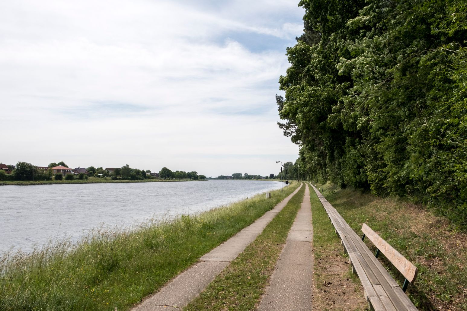 Die längste Bank der Welt verläuft entlang des Nord-Ostsee-Kanals, flankiert von einem Gehweg und üppigem Grün.